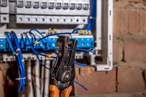 Electrician stripping wires at a residential breaker panel